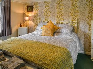 a bedroom with a large bed with a yellow blanket at The Old Thatch in Hailsham