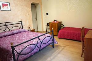 - une chambre avec un lit avec des draps violets et une table dans l'établissement LE MIMOSE, à Spezzano Albanese