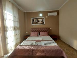 a bedroom with a large bed with pink sheets at Hotel Fama in Durrës