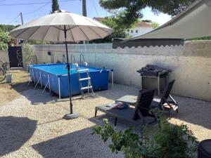 a patio with an umbrella and a swimming pool at Maison proche Avignon 2 chambres in Les Angles Gard