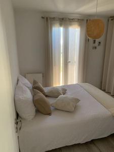 Un dormitorio con una cama blanca con almohadas y una ventana. en Maison avec jardin proche Avignon 2 chambres, en Les Angles
