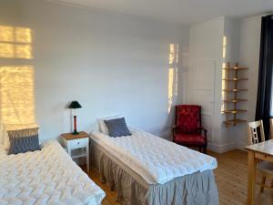 a bedroom with two beds and a red chair at Lägenhet med havsutsikt in Strömstad
