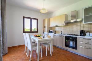 una cocina con una mesa y sillas blancas y una encimera. en 6 - Meraviglioso appartamento con terrazza - Sa Crai Apartments Sardinian Experience en Lotzorai