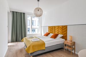 a bedroom with a large bed with a yellow blanket at LTC - Apartments Modern Tower in Gdynia