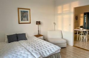 1 dormitorio con 1 cama blanca y 1 silla en Lägenhet med havsutsikt en Strömstad
