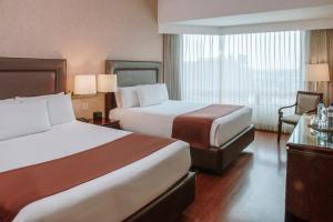 a hotel room with two beds and a window at Hotel Clarion Suites Guatemala in Guatemala