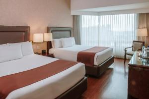 Hotel Clarion Suites Guatemala tesisinde bir odada yatak veya yataklar