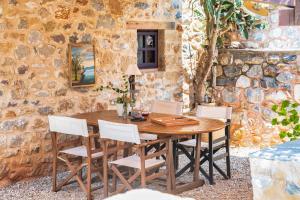 un tavolo in legno con sedie di fronte a un muro di pietra di Malsova Studio a Kotrónion
