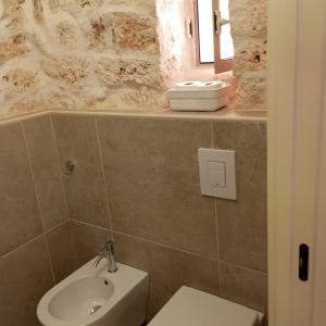 ein Badezimmer mit einem Waschbecken und einem weißen WC in der Unterkunft Sotto la pergola in San Michele Salentino