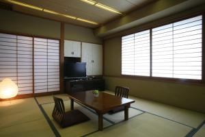 a dining room with a table and chairs and windows at King Ambassador Hotel Kumagaya in Kumagaya