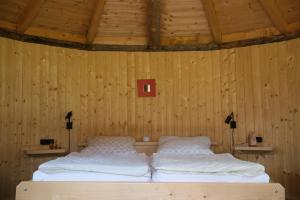 1 dormitorio con 2 camas en una pared de madera en Holzjurten by JULKA - self checkin, en Finkenstein