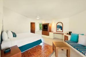 Desire Riviera Maya Pearl Resort All Inclusive - Couples Only في بويرتو موريلوس: غرفة نوم بسرير كبير وأريكة