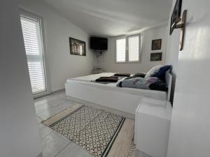 a white bedroom with a bed and a tv at Emko Apartmens Vir in Vir