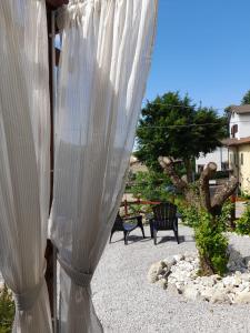 einen weißen Vorhang auf einer Terrasse mit zwei Bänken in der Unterkunft Il Cavallo a Dondolo in Abbadia San Salvatore