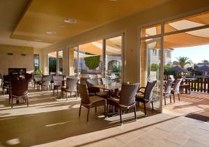 een eetkamer met tafels, stoelen en ramen bij Apartamentos Sol Romántica by DOT Suites in Cala Romantica
