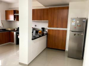 a kitchen with a stainless steel refrigerator and wooden cabinets at Casa Beni para estrenar in Santa Cruz de la Sierra