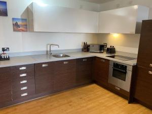 a kitchen with brown cabinets and a sink and a stove at Spacious 2 Bedroom Apartment at The PostBox in Birmingham