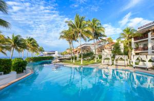 una piscina en el complejo con palmeras y edificios en Desire Riviera Maya Pearl Resort All Inclusive - Couples Only, en Puerto Morelos