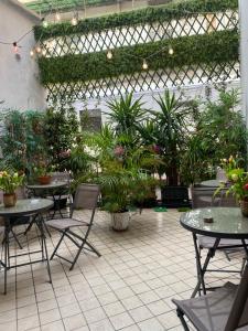 eine Terrasse mit Tischen, Stühlen und Topfpflanzen in der Unterkunft Monteoliveto 33 in Neapel