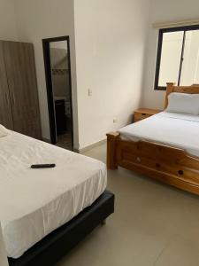 a bedroom with two beds and a remote control at Hotel Hacienda Guane Urbano in Oiba