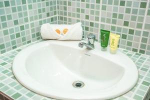 a white sink with a towel and a toothbrush at Hotel Caracas in Panama City