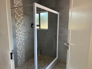 a shower with a glass door in a bathroom at Thabazimbi Country Lodge in Thabazimbi