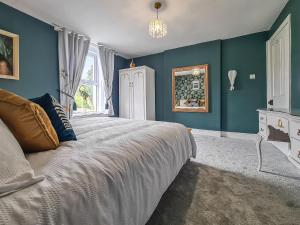 um quarto com uma cama grande e paredes azuis em Orchard House em Langrigg