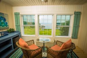 un porche cubierto con 2 sillas y una mesa de cristal en Island View Inn en Glen Cove