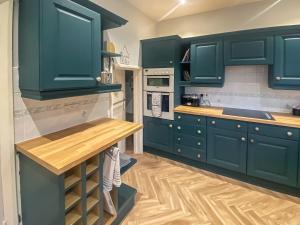 a kitchen with green cabinets and a wooden floor at Sea View Cottage in Llandrillo-yn-Rhôs
