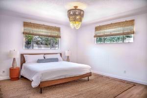 a bedroom with a bed and two windows and a chandelier at Mojave Desert Pied-à-terre in Yucca Valley