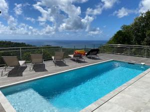 uma piscina num pátio com cadeiras e o oceano em Villa Madjic em Sainte-Luce