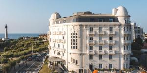 - un grand bâtiment blanc à côté de l'océan dans l'établissement Studio phare de Biarritz Résidence Régina Golf, à Biarritz