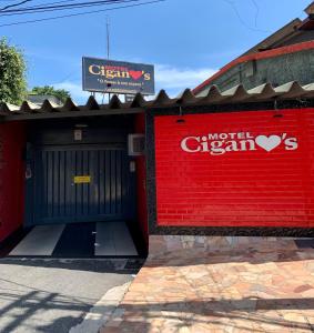 um edifício vermelho com uma garagem com um sinal em Motel Cigano’s em Belo Horizonte