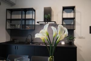 a vase with white flowers on a table in a kitchen at Oktò apartments Milazzo in Milazzo