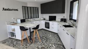 a kitchen with white counters and black cabinets and stools at Villa Ker Bunk in Audierne