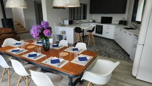 a kitchen and dining room with a wooden table and white chairs at Villa Ker Bunk in Audierne