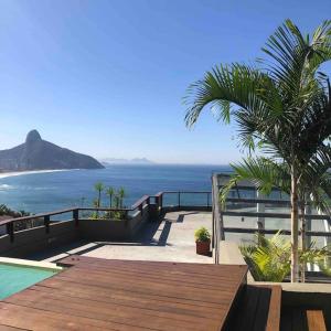 uma vista para o oceano a partir de uma casa com um deque de madeira em Mansão fascinante com vista para o mar e montanhas - Joá - Rio de Janeiro no Rio de Janeiro