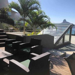 um pátio com cadeiras, uma mesa e uma palmeira em Mansão fascinante com vista para o mar e montanhas - Joá - Rio de Janeiro no Rio de Janeiro