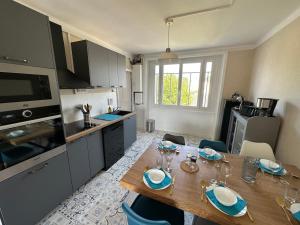 a kitchen with a wooden table with chairs and a dining room at Chez Tante Muguette proche Dinan in Le Hinglé