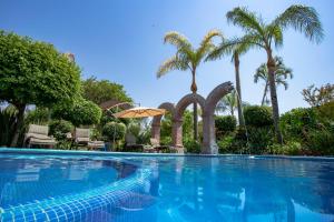 a swimming pool with palm trees in the background at La Casa de los Patios Hotel & Spa in Sayula