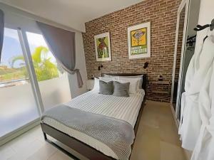 1 dormitorio con 1 cama grande y pared de ladrillo en Cana Rock Condos Rock & Roll Theme & Golf Course View - infinity Pool en Punta Cana