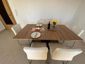 a dining room table with white chairs and a wooden table at Apartments Majić in Kaštela