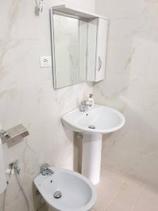 a white bathroom with a sink and a mirror at Center Lake House in Shkodër