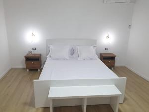ein weißes Bett in einem Zimmer mit zwei Nachttischen in der Unterkunft Center Lake House in Shkodra