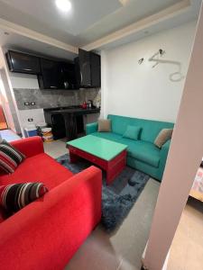 a living room with a green couch and red chairs at استديو فى بورتو جولف مارينا in El Alamein