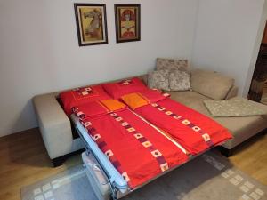 uma cama com um cobertor vermelho em cima de um sofá em Shiny Thumb Apartment em Bihać