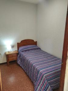 Habitación pequeña con cama y mesita de noche en Apartamentos Can Bruguera 4, en Mataró