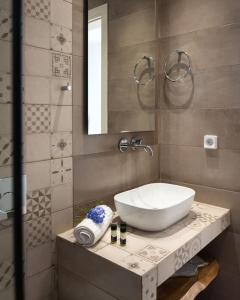 ein Badezimmer mit einem weißen Waschbecken und einem Spiegel in der Unterkunft Santa Maria Mare in Naoussa