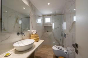 een witte badkamer met een wastafel en een douche bij Santa Maria Mare in Naousa