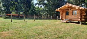 a log cabin in a field with a fence at Chalet du trappeur in Grosbreuil +4 photos